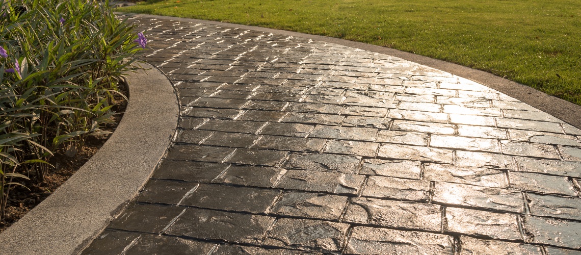 dark stamped concrete walkway reflecting sunlight
