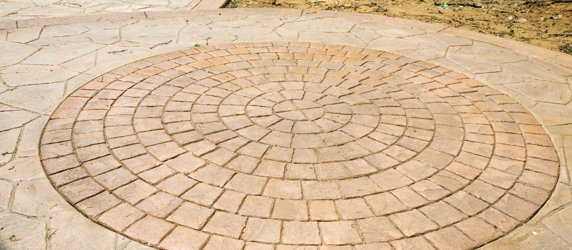 Stamped concrete with a circular cobblestone pattern inlay